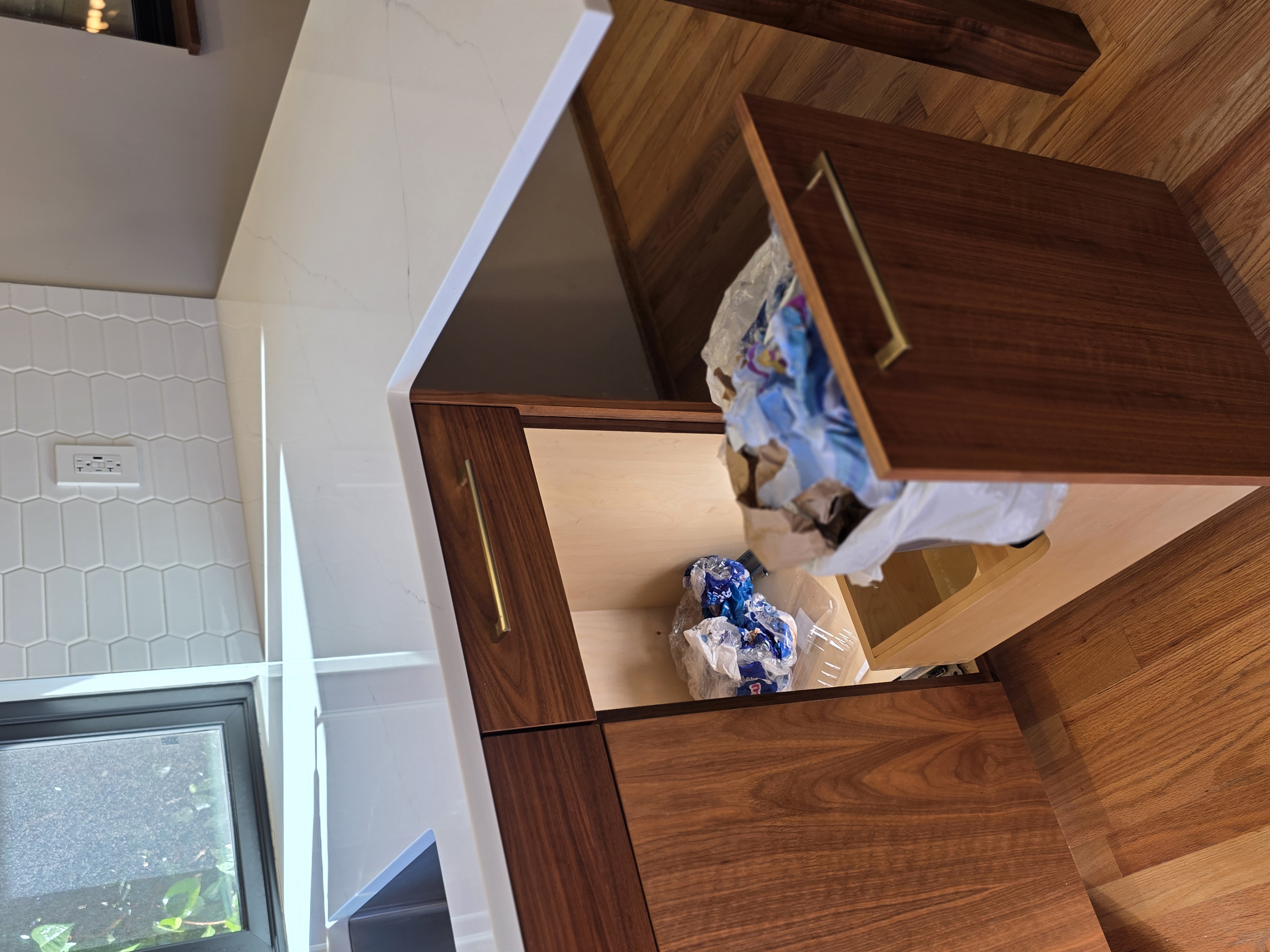 Messy cabinet without Trash Shield, debris and crumbs collected behind the pull-out trash can